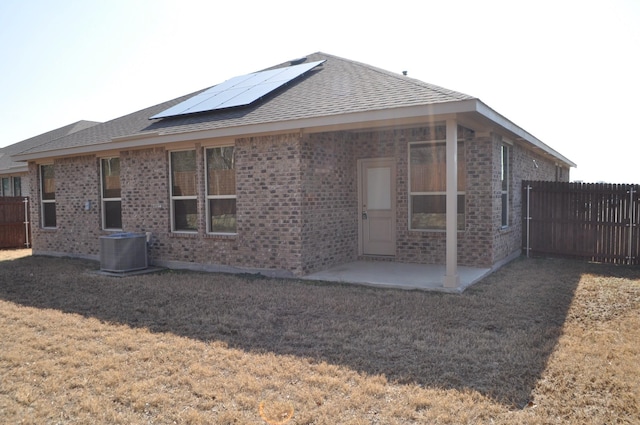 rear view of property with a patio, central air condition unit, and solar panels