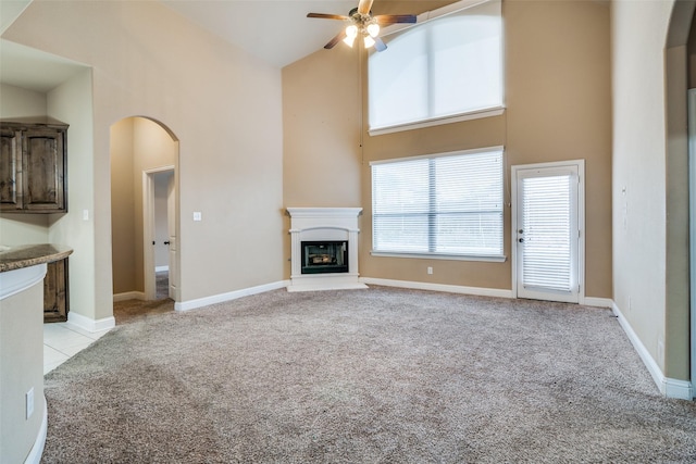 unfurnished living room with ceiling fan, light colored carpet, and high vaulted ceiling