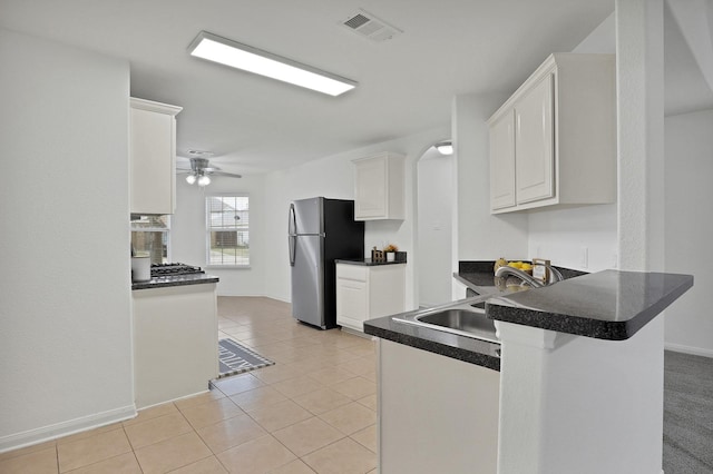 kitchen with sink, light tile patterned floors, stainless steel fridge, white cabinetry, and kitchen peninsula