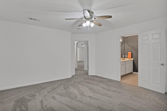 unfurnished bedroom with ceiling fan, light colored carpet, and ensuite bath