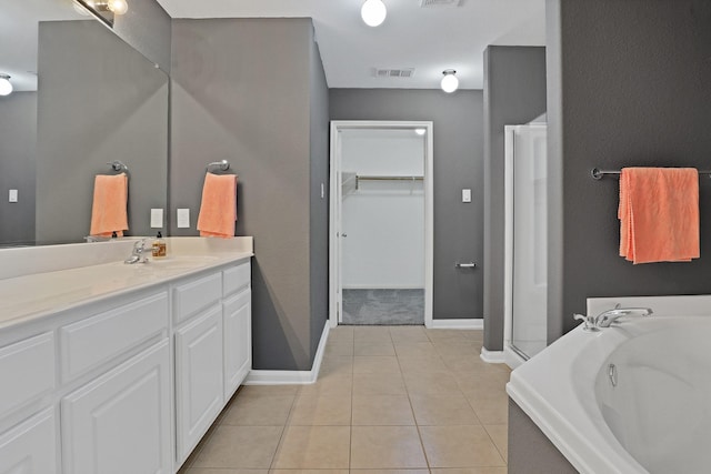 bathroom featuring tile patterned flooring, vanity, and a tub to relax in