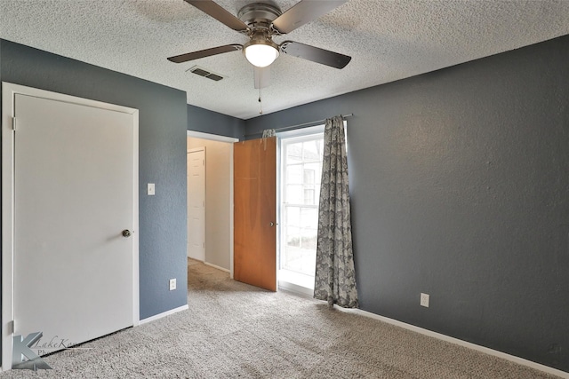 unfurnished bedroom featuring ceiling fan, light colored carpet, and a textured ceiling