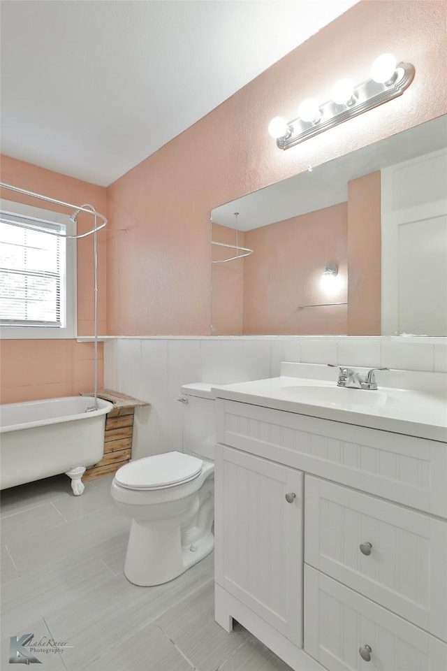 bathroom featuring vanity, a bath, and toilet