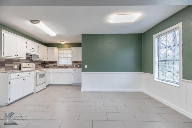 kitchen featuring sink, white cabinetry, tasteful backsplash, light stone counters, and white appliances