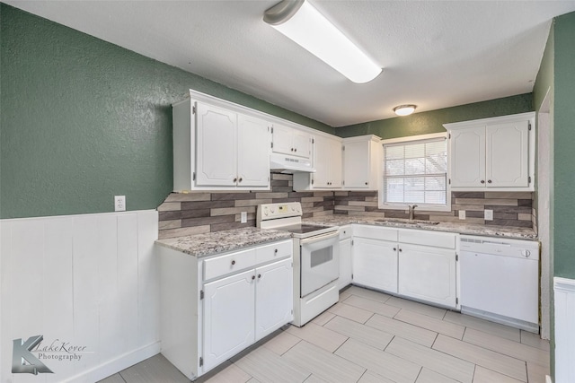 kitchen featuring sink, light stone counters, white appliances, decorative backsplash, and white cabinets