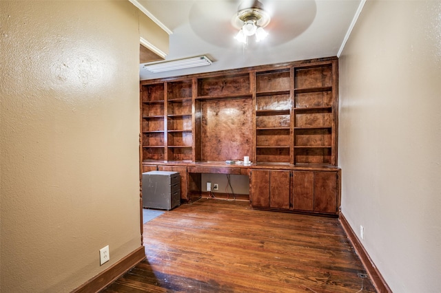 unfurnished office with ceiling fan, ornamental molding, dark hardwood / wood-style flooring, and built in desk