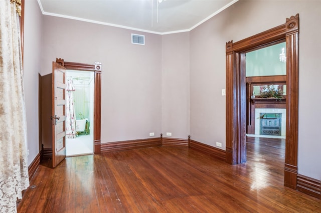 unfurnished room with a tiled fireplace, crown molding, and dark wood-type flooring