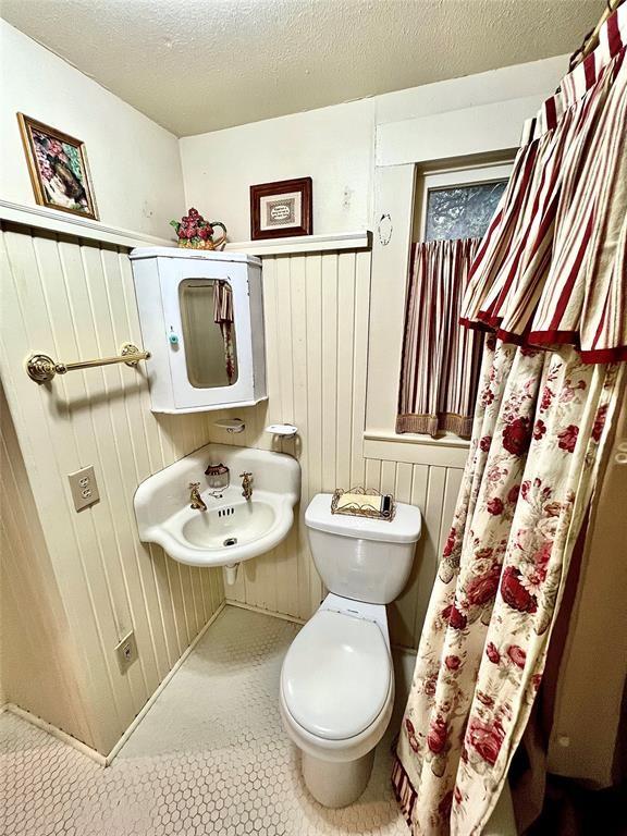 bathroom with tile patterned flooring, a textured ceiling, and toilet