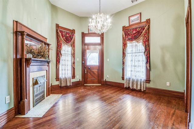 entrance foyer featuring hardwood / wood-style flooring, a tiled fireplace, and a notable chandelier