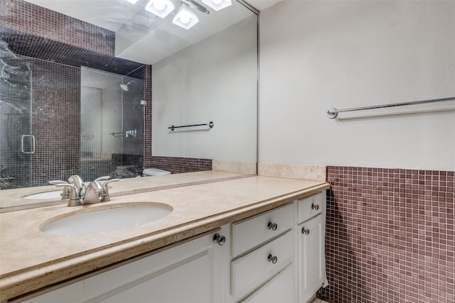 bathroom with vanity, tile walls, and a shower with shower door