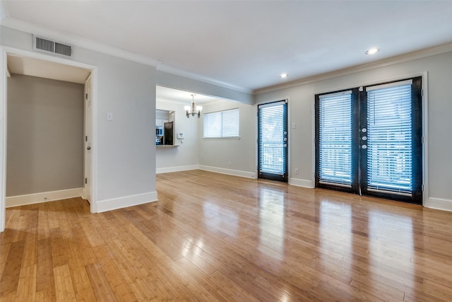 spare room with ornamental molding, a chandelier, and light wood-type flooring