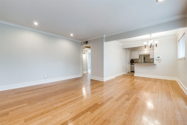 unfurnished living room featuring crown molding, light hardwood / wood-style floors, and a chandelier