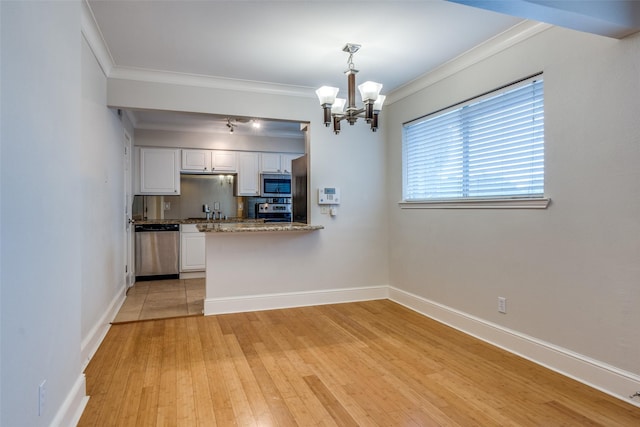 kitchen featuring pendant lighting, white cabinetry, ornamental molding, kitchen peninsula, and stainless steel appliances