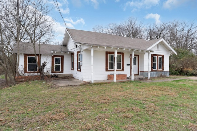 view of front of house with covered porch, a shingled roof, and a front yard