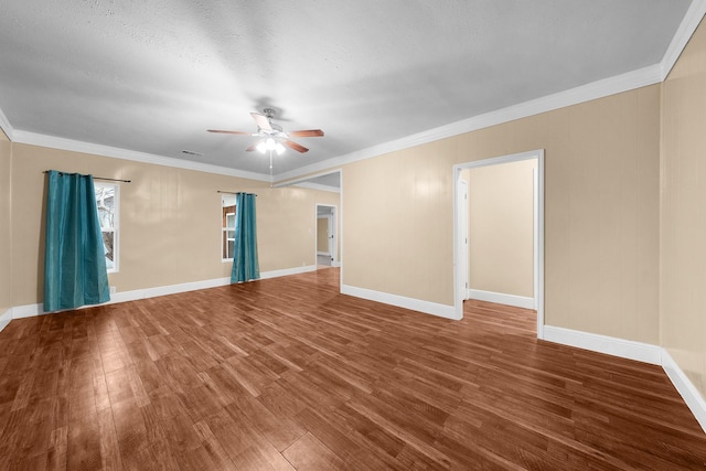 spare room with ornamental molding, wood finished floors, baseboards, and ceiling fan