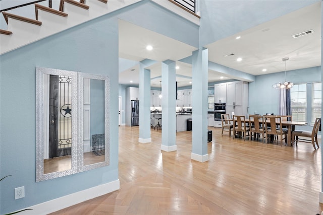 dining area featuring a notable chandelier, a towering ceiling, and light parquet floors