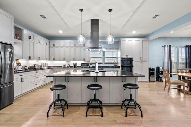 kitchen with a center island, island range hood, a kitchen bar, and black appliances