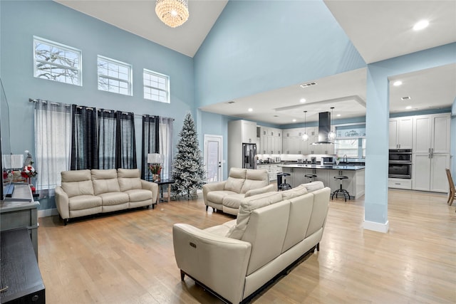 living room with a towering ceiling, a wealth of natural light, and light wood-type flooring