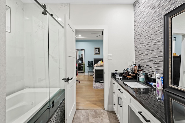 bathroom featuring vanity, backsplash, and shower / bath combination with glass door