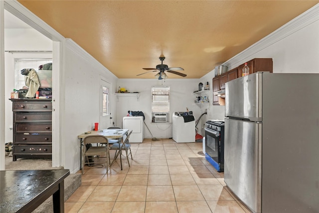 kitchen featuring crown molding, appliances with stainless steel finishes, washing machine and dryer, and light tile patterned floors