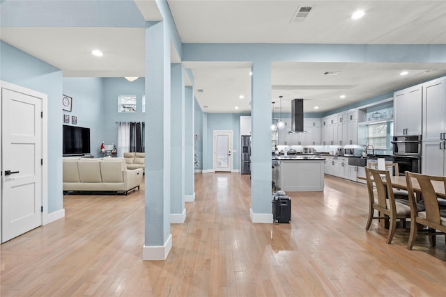 kitchen with white cabinetry, island range hood, light hardwood / wood-style flooring, and pendant lighting