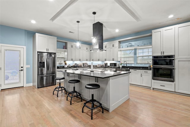 kitchen with white cabinetry, island range hood, hanging light fixtures, a kitchen island, and stainless steel appliances