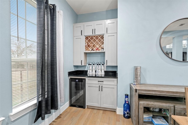 bar with wine cooler, white cabinetry, and light wood-type flooring