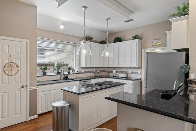 kitchen featuring sink, stainless steel refrigerator, a center island, black electric stovetop, and white cabinets