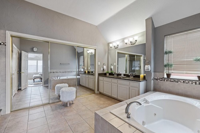 bathroom with lofted ceiling, tile patterned flooring, vanity, and tiled tub