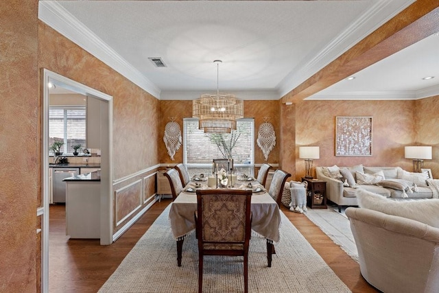 dining space featuring wood-type flooring, crown molding, and an inviting chandelier