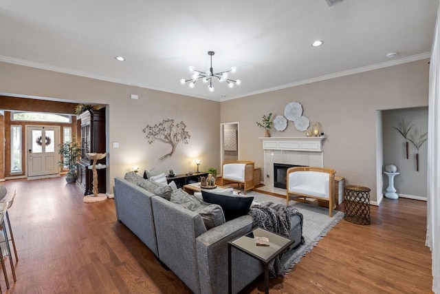 living room featuring crown molding, a fireplace, hardwood / wood-style floors, and a notable chandelier