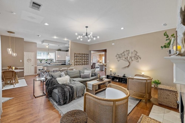 living room featuring ornamental molding, light hardwood / wood-style floors, and a chandelier