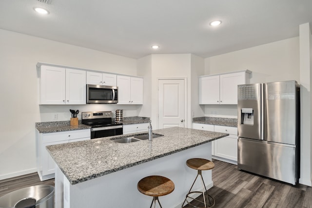 kitchen featuring sink, appliances with stainless steel finishes, white cabinetry, a kitchen island with sink, and light stone counters