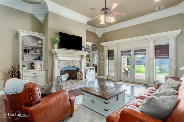 living room featuring french doors, a brick fireplace, light hardwood / wood-style flooring, ornamental molding, and ceiling fan