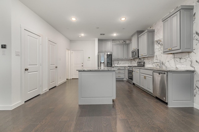 kitchen featuring gray cabinetry, light stone counters, stainless steel appliances, and a kitchen island