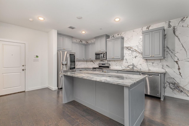 kitchen featuring dark hardwood / wood-style flooring, light stone countertops, stainless steel appliances, and a kitchen island