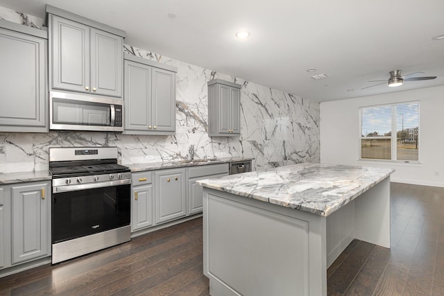 kitchen featuring tasteful backsplash, a kitchen island, gray cabinets, and appliances with stainless steel finishes