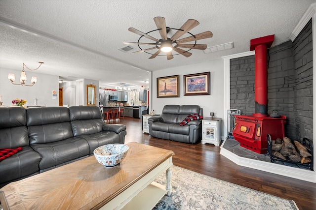 living room featuring dark hardwood / wood-style floors, ceiling fan with notable chandelier, a textured ceiling, and a wood stove