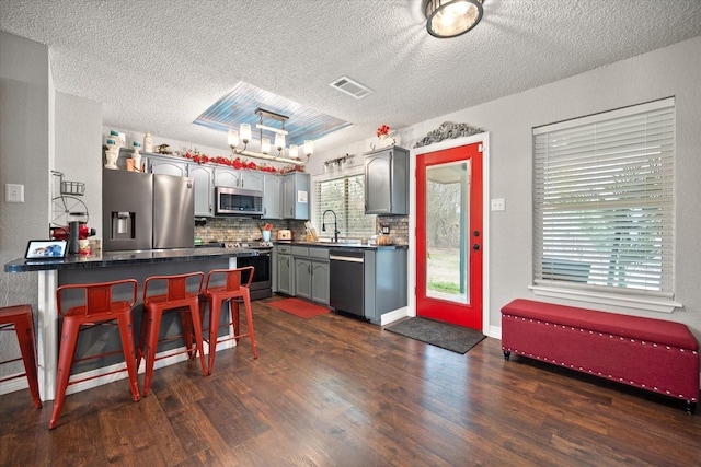 kitchen featuring appliances with stainless steel finishes, dark hardwood / wood-style floors, sink, gray cabinetry, and backsplash