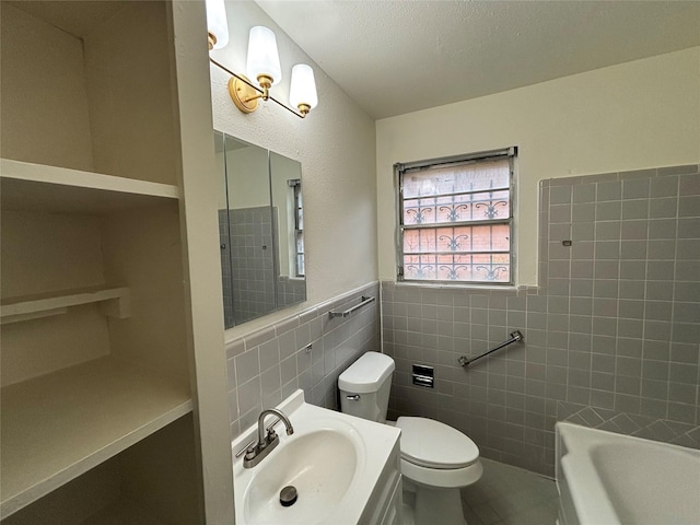 bathroom with tile walls, a bathtub, vanity, a textured ceiling, and toilet