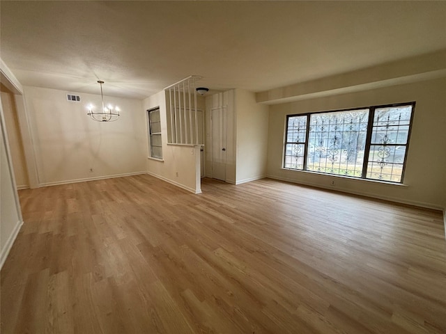 unfurnished living room with a chandelier and light wood-type flooring