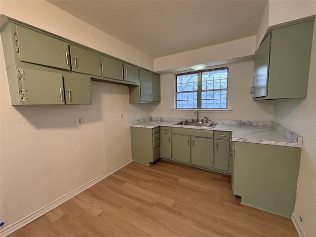 kitchen with green cabinets, sink, light hardwood / wood-style flooring, and a textured ceiling