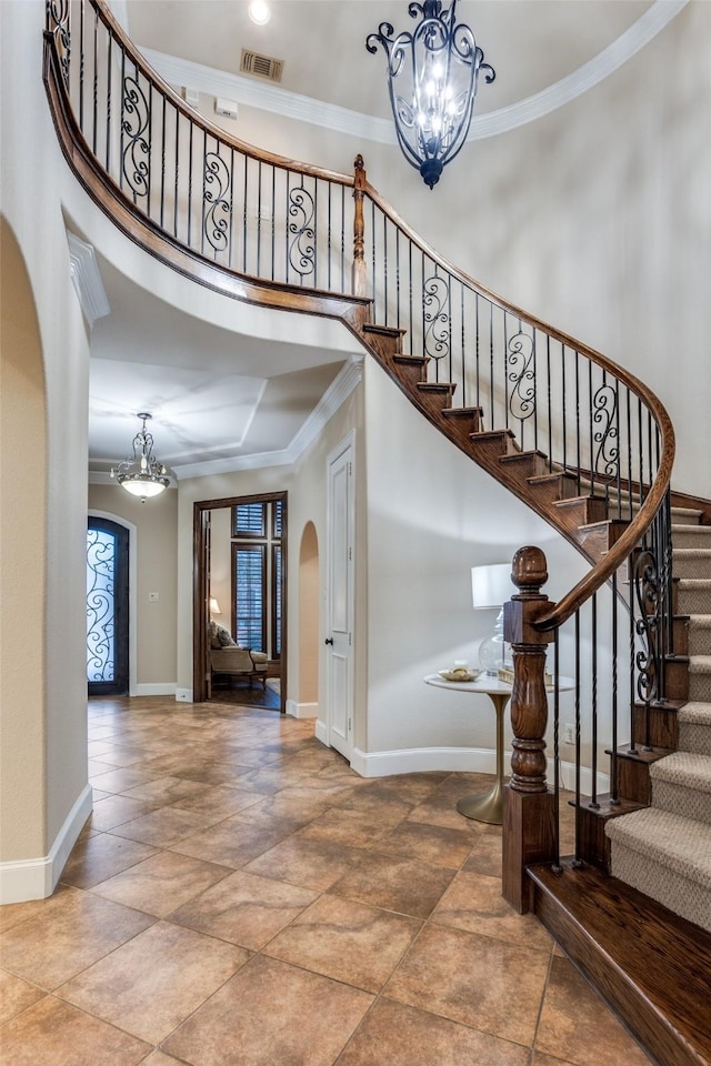 staircase with a high ceiling, ornamental molding, and a chandelier