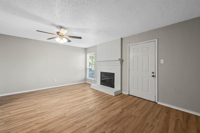 unfurnished living room featuring hardwood / wood-style flooring, a fireplace, a textured ceiling, and ceiling fan