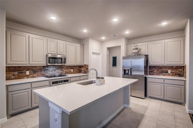 kitchen featuring an island with sink, appliances with stainless steel finishes, sink, and light tile patterned floors