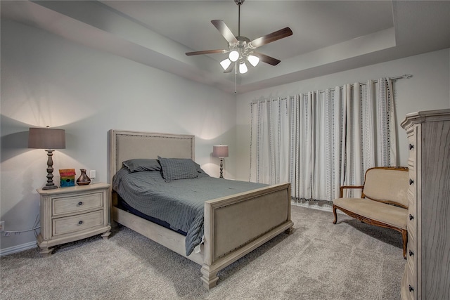 carpeted bedroom with ceiling fan and a tray ceiling