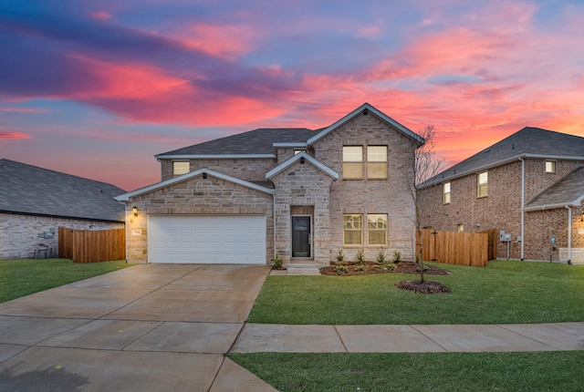 traditional-style house featuring an attached garage, fence, a yard, and driveway