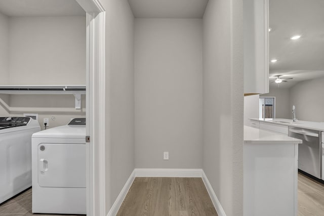 clothes washing area with ceiling fan, washing machine and clothes dryer, and light wood-type flooring