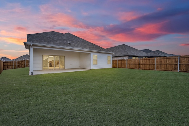 back house at dusk with a yard and a patio