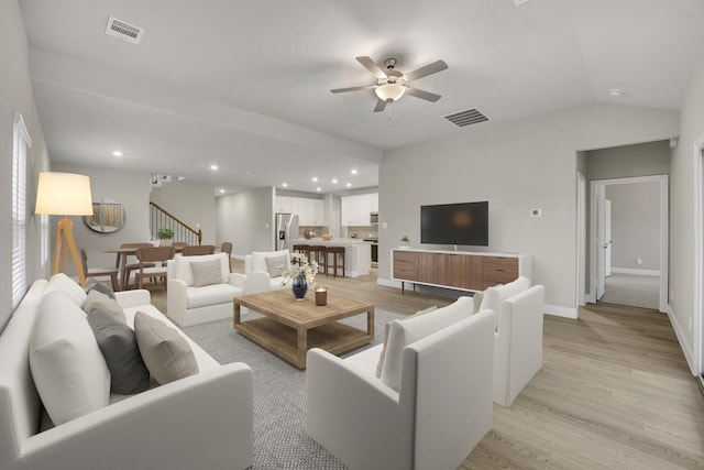 living room with vaulted ceiling, ceiling fan, and light wood-type flooring